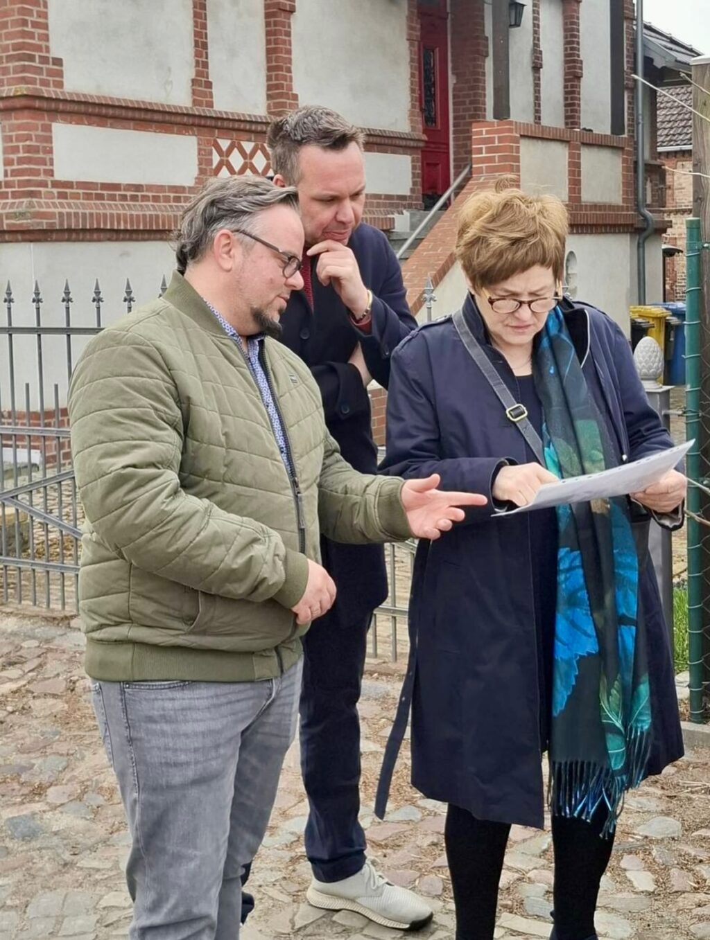 Gestern war ich mit meiner Familie und vielen anderen Interessierten zum 13. Osterspaziergang in Wusterhausen/Dosse! Dazu hatte der Kulturverein Wusterhausen e.V. eingeladen. 

Der Osterspaziergang begann - ungewöhnlich - auf dem Friedhof - mit einer Ansprache von Pfarrer Alexander Bothe. 

So ungewöhnlich war der Start des Spaziergangs dann aber doch nicht, da Friedhöfe das Leben zeigen, indem sie als Orte der Erinnerung die Verbindung zwischen Verstorbenen und Hinterbliebenen aufrechterhalten. 

Nach dem Friedhof führte uns der Weg über die Berliner Straße und viele historische Fotos aus verschiedenen Jahrzehnten wurden gezeigt. 

Heute ist es dem Bürgermeister, Philipp Schulz, gelungen, dass diese Straße in diesem Jahr saniert wird. Daran hatten sich bereits mehrere Bürgermeister abgearbeitet. 4,2 Millionen € Invest! Trotz Fördermittel ein Kraftakt für die Gemeinde und ein großartiger Erfolg! Gut gemacht, Herr Bürgermeister.

Wer wollte konnte den Spaziergang in der Galerie ‚Alter Laden‘ (Am Markt 3) ausklingen lassen.

Vor der Wahl werde ich nochmal nach Wusterhausen/Dosse kommen.  Gerne in die Kita ‚Am Markt‘ zum Fachgespräch, spätestens am 06. Juni 2026 zum Stadtfest - dem Tag vor der Wahl!

FunFact zum Bild: Links ist eine sogenannte Salzfrau zu sehen! Wusterhausen kam damals angeblich zu Reichtum durch den Salzhandel.
Der Kulturverein nimmt die Salzfrauen als traditionelle Figuren der damaligen Zeit.